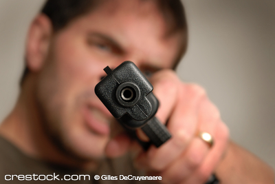 Angry man pointing gun at camera. Shallow dept...